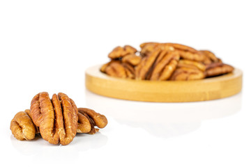 Lot of whole dry brown pecan nut on bamboo coaster isolated on white background