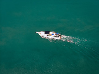 Aerial view of the speedboat and a boat behind it sailing near the coast of Thailand, white trace on the water; vessels concept.
