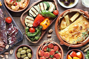 Spanish tapas. Traditional mediterranean appetizer table concept included tortilla, grilled vegetables, meatballs, garlic king prawns,olives and cured meat.
