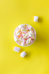 Fluffy dessert. Marshmallows in plate on yellow table top view copy space