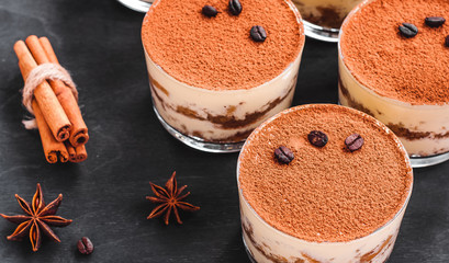 gourmet tiramisu dessert in a glass sprinkled with cocoa and decorated with coffee beans on a dark...