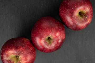 Group of three whole fresh apple red delicious flatlay on grey stone