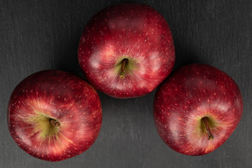 Group of three whole fresh apple red delicious flatlay on grey stone