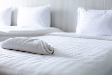 Fototapeta na wymiar White towel on bed in guest room for hotel customer.