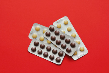 Set of pills blisters isolated on solid red background. Medical concept. Potent drugs. Brown and yellow pills. 