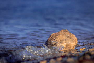 The stone lies in the oncoming waves of the surf