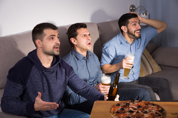 Males watching tv at home and having fun