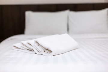 White towel on bed in guest room for hotel customer.