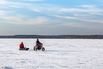  Men drive the vehicle on frozen ice. Frozen lake - winter weather.