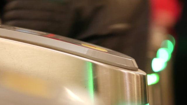 People go into the subway through an electronic barrier. Ring with NFC RFID. A hand in a black glove applies to a contactless reader at the gate of a subway turnstile. Green LED backlight.