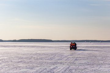  Men drive the vehicle on frozen ice. Frozen lake - winter weather.