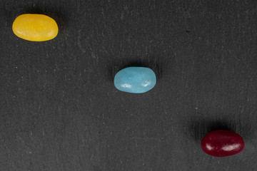 Group of three whole jelly bean candy flatlay on grey stone