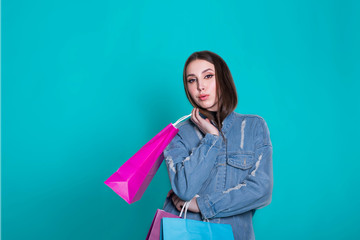 Portrait of a smiling pretty girl in dress with shopping bags over blue background. Black friday concept.