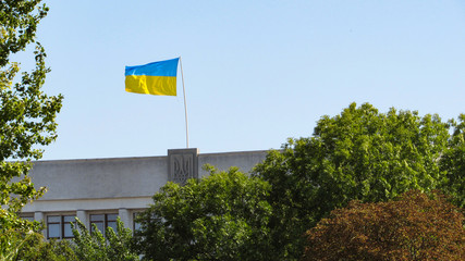 Ukraine flag on sky background. state emblem of Ukraine on the building