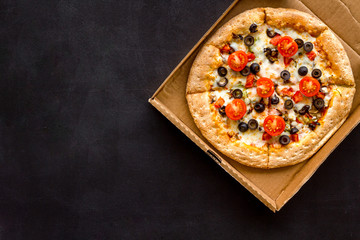 Pizza delivery. Italian food in box on black background top view copy space