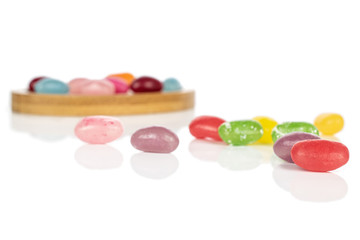 Lot of whole jelly bean candy on round bamboo coaster isolated on white background
