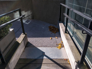 Wheelchair / walking ramp in downtown Bellevue, Washington on a sunny, autumn day with leaves scattered
