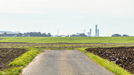 Der Feldweg durchzieht Landschaft am Horizont sieht man das Kraftwerk und die Windräder