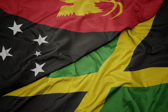 waving colorful flag of jamaica and national flag of Papua New Guinea .