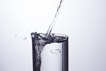 Agua entrando en un recipiente transparente de crital o plástico; agua salpicando 