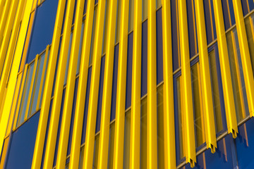 Geometric color elements of the building facade with planes, lines, corners with highlights and reflections for the abstract background and texture of blue, yellow, orange, gray colors. Place for text