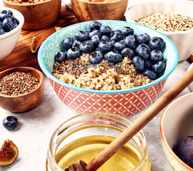 healthy breakfast, quinoa porridge with blueberries, nuts, seeds and superfoods, selective focus