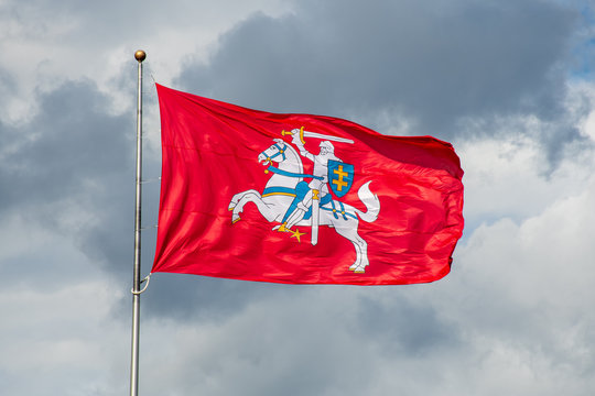 Historical Lithuanian flag, coat of arms of Lithuania, consisting of an armour-clad knight on horseback holding a sword and shield, is also known as Vytis, waving in the wind against cloudy sky 