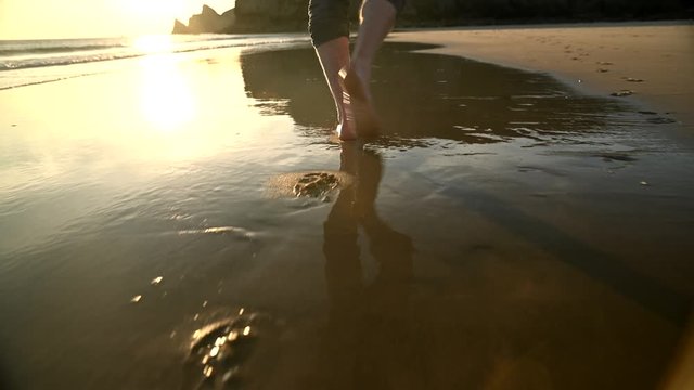 Section of man walking and running at beach barefoot