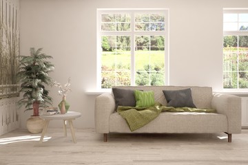 Stylish room in white color with sofa and summer landscape in window. Scandinavian interior design. 3D illustration