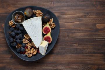 figs with cheese and pomegranate on black dish on dark wooden background