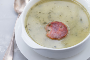 typical portuguese soup caldo verde in white bowl on ceramic background