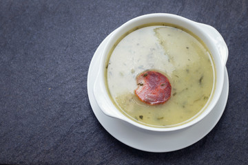 typical portuguese soup caldo verde in white bowl on ceramic background