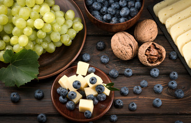 blueberry grapes and cheese on a wooden background