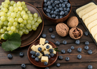 blueberry grapes and cheese on a wooden background
