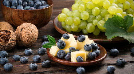 blueberry grapes and cheese on a wooden background