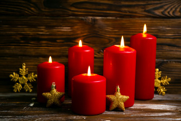 Bunch of red candles burning on wooden table with traditional christmas snow flake decoration on wood textured background with a lot of copy space for text.