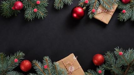 Christmas banner. Black Xmas background with red decorations, fir tree branches and gift boxes wrapped craft paper. Christmas frame, greeting card template, web banner mockup. Flat lay, top view, copy