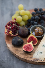 figs with cheese, grapes and honey on wooden board