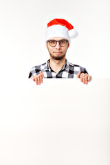 Santa bearded man, brutal hipster with moustache on surprised face in christmas red hat for new year holiday with white paper sheet isolated on white background, copy space