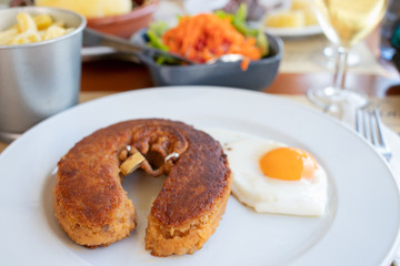 typical smoked sausage alheira with egg in white dish in restaurant