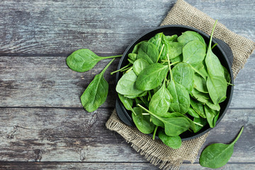 Fresh organic baby spinach leaves on a plate on dark wooden table top view. Healthy and organic...