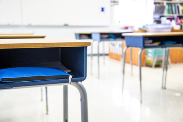 Contemporary student desks placed into rows within brightly lit room filled with studying materials