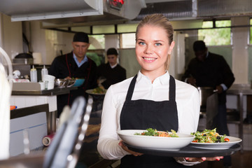 Waitress with dishes in kitchen