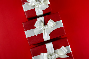 Bunch of christmas presents wrapped in red and white paper tied with shiny silk bow. Multiple new years gifts in red and white wrapping. Top view, close up, copy space, background, flat lay.