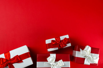 Bunch of christmas presents wrapped in red and white paper tied with shiny silk bow. Multiple new years gifts in red and white wrapping. Top view, close up, copy space, background, flat lay.