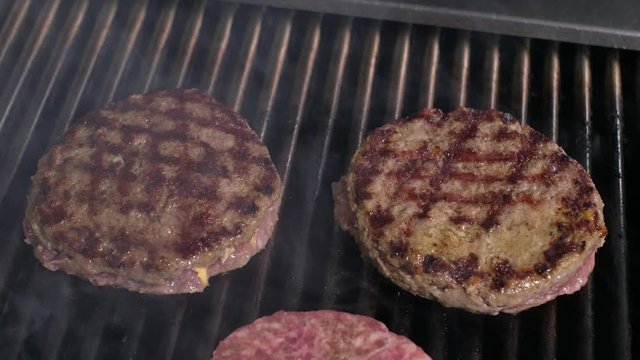 Preparing a batch of ground beef patties or frikadeller on grill or BBQ
