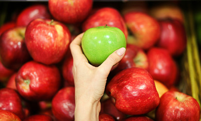 Female hand choosing apples in the store. Concept of healthy food, bio, vegetarian, diet.