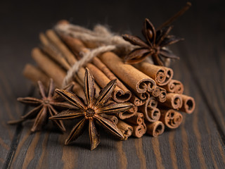 cinnamon sticks tied up with a rope and anise stars on wooden background