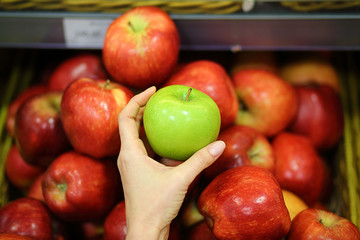 Female hand choosing apples in the store. Concept of healthy food, bio, vegetarian, diet.