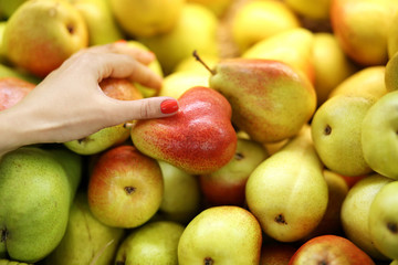 Female hand chooses pear in the store. Concept of healthy food, bio, vegetarian, diet.